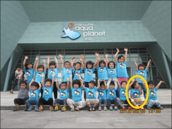 ▲에스더 어린이집의 체험활동 사진, 다른 아이들은 선생님의 말에 따라 손을 올리고 있지만, 에스더만 손을 안 들고 앉아 있다.