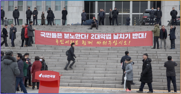 ▲자유한국당 관계자는 집회가 시작되기 전에는 본청 앞 계단에 당원들이 서 있지 못하도록 했다. 국회 출입 통제에 시민들이 모이지 않고 있다고 보여주기 위해서다.