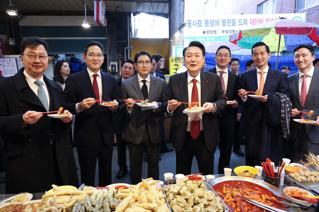 ▲윤석열 대통령이 6일 부산 중구 깡통시장에서 기업 총수들과 함께 떡볶이 튀김 빈대떡을 먹고 있다. 오른쪽 부터 정기선 HD현대 부회장, 김동관 한화그룹 부회장, 구광모 LG그룹 회장, 윤 대통령, 조현준 효성그룹 회장, 이재용 삼성전자 회장, 최재원 SK수석부회장  ⓒ연합뉴스 